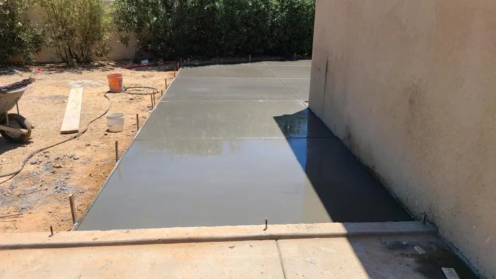 Narrow finished concrete pad running along a property wall