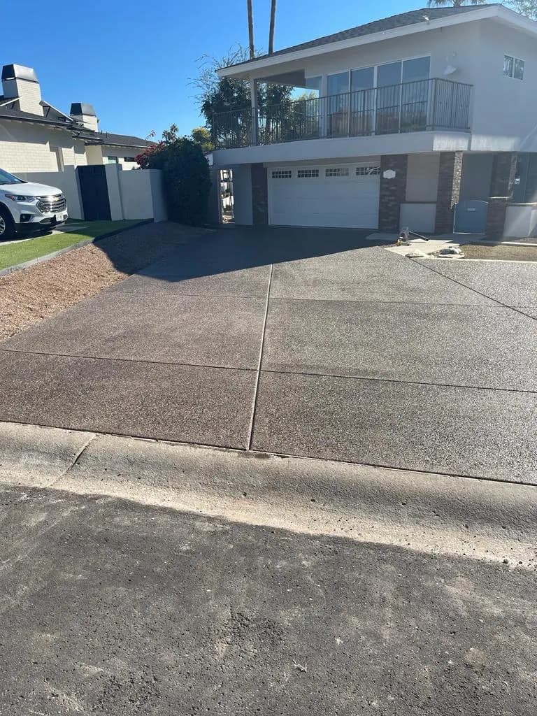 Finished concrete driveway and street approach in front of a two-story home with a two-car garage